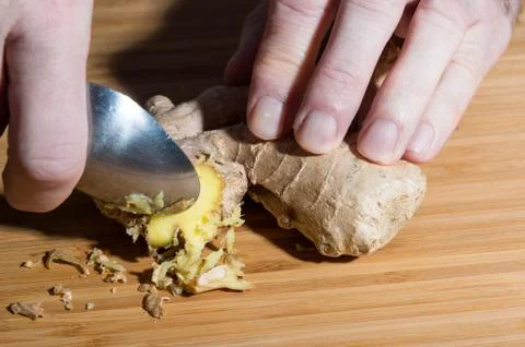 Grating ginger root with a spoon Stock Photos