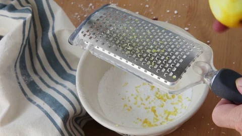 Grating lemon peel over powdered sugar Stock Footage 93794114