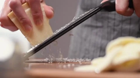 Grating parmesan cheese with a grater in the kitchen. Stock Footage 154370011