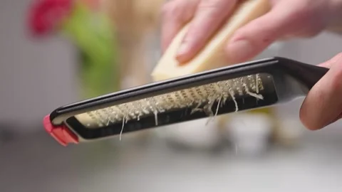 Grating parmesan cheese with a grater in the kitchen. Stock Footage 154370658