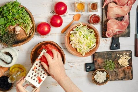 Grating tomatoes with grater in a kitchen setting Stock Photos