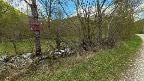 Gravel path winds through green hills. Tupavica Waterfall, trail marker. Stock Footage 335532715