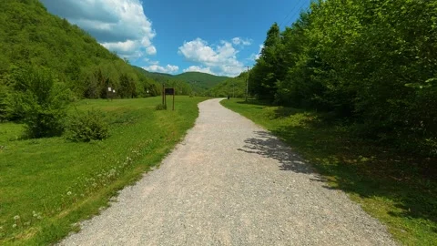 Gravel path winds through vibrant green fields. Gostilje Waterfall, Serbia. Vídeos de archivo 337059594