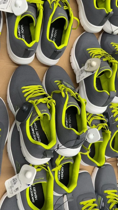 Gray and lime green athletic shoes with tags on display in a retail environme Stock Footage 330927553