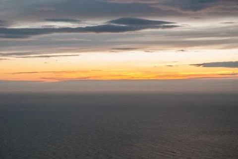 Gray and orange clouds at sunset over the gray sea Stock Photos