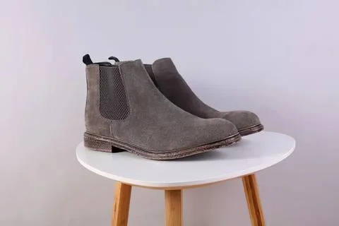 Gray ankle boots with elastic sides on white table Stock Photos