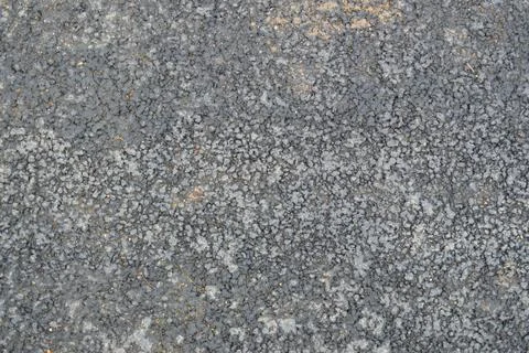 Gray asphalt road with small pebbles and cracks. Texture, background Stock Photos