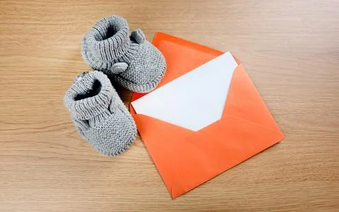 Gray baby bootees with a empty paper in a orange envelope Stock Photos