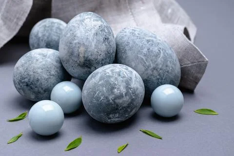 On a gray background, close-up marble-colored Easter eggs with green leaves a Stock Photos