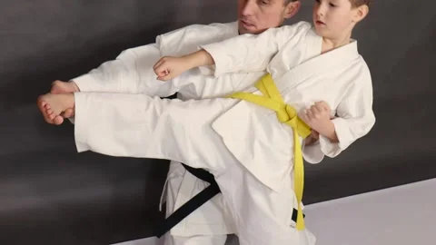 On a gray background, a coach trains an athlete to kick to the side Stock Footage 268718640