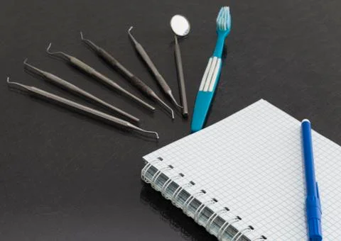 On a gray background is a notebook, dental instruments Stock Photos