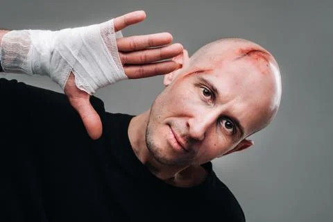 On a gray background stands a battered man in a black T-shirt With his hands  Stock-Fotos