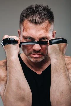 On a gray background stands a battered man in a black T shirt looking like a  Fotos Stock
