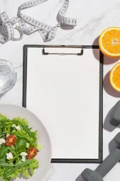 Gray background with tablet, lettuce, orange, dumbbells and measuring tape Stock Photos