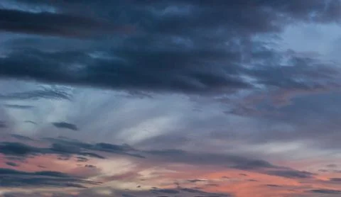 Gray, blue and orange clouds at sunset Stock Photos