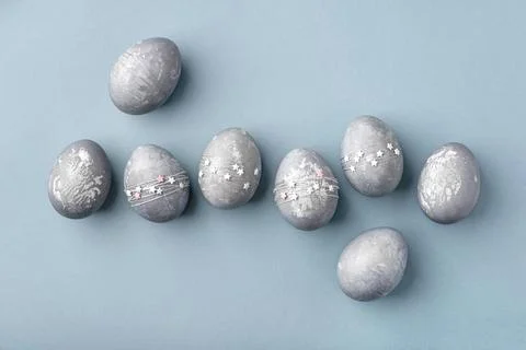 Gray-blue Easter eggs with stars on a blue table. Stock Photos