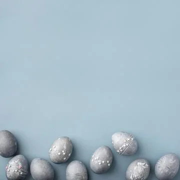 Gray-blue Easter eggs with stars on a blue table. Stock Photos