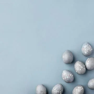 Gray-blue Easter eggs with stars on a blue table. Stock Photos