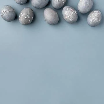Gray-blue Easter eggs with stars on a blue table. Stock Photos