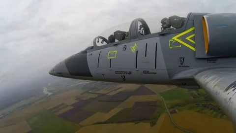 Gray blue training fighter plane fly over the green fields and make flips in sky Stock Footage 118676883