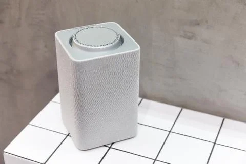 A gray bluetooth speaker, square, music column stands on a tile of white squares Stock Photos