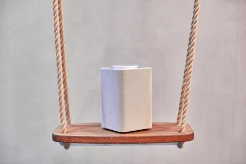 A gray bluetooth speaker, square, music column stands on a tile of white squares Stock Photos