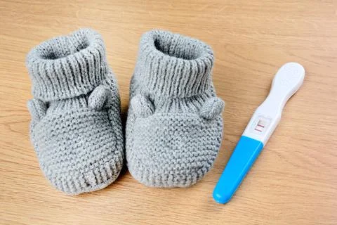 Gray bootees with a pregnancy test on a table Stock Photos