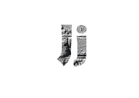 Gray brick background. Shot through the cut-out silhouette of the letter J Stock Photos