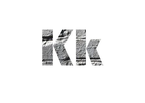 Gray brick background. Shot through the cut-out silhouette of the letter K Stock Photos