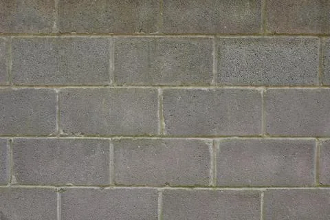 A gray brick wall with a few cracks Stock Photos