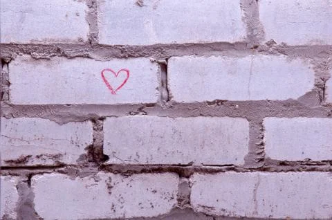 Gray brick wall with a painted red heart. Declaration of love. Greeting card. Stock Photos