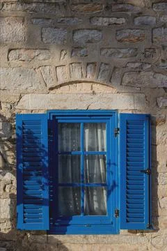 A gray building with blue window frames in the Greek style. Travel and Stock Photos