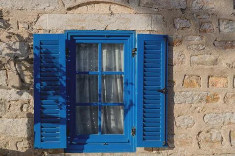 A gray building with blue window frames in the Greek style. Travel and Stock Photos