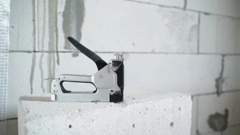 A gray building stapler on an aerated concrete brick close-up against the 動画素材 233567344