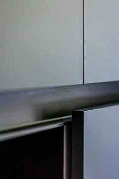 Gray cabinet fronts above dark countertop. Minimalist kitchen joinery detail. Stock Photos