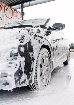 Gray car on the side in the foam from the detergent stands at the sink Stock Photos