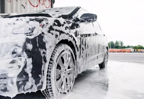 Gray car on the side in the foam from the detergent stands at the sink Stock Photos