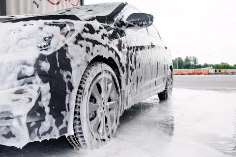 Gray car on the side in the foam from the detergent stands at the sink Stock Photos