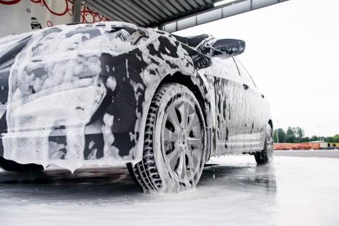 Gray car on the side in the foam from the detergent stands at the sink Stock Photos