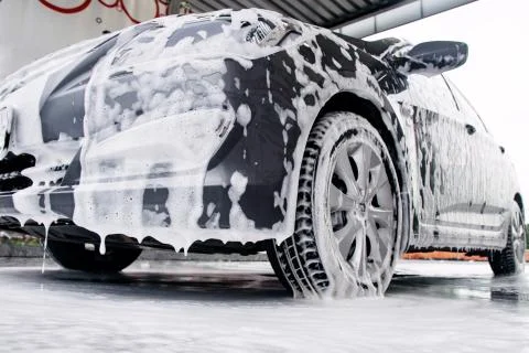 Gray car side view in a cleaning agent at the car wash Stock Photos
