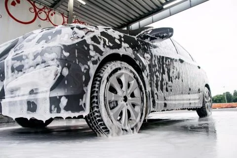 Gray car side view in a cleaning agent at the car wash Stock Photos