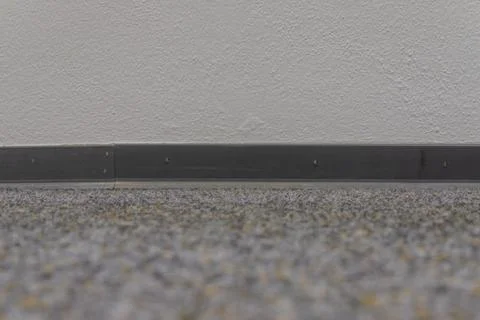 Gray carpet floor with dark baseboard and textured wall Stock Photos
