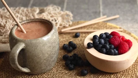 Gray ceramic mug holds light brown smoothie with golden straw, next to wooden Stock-Footage 289236373