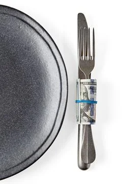Gray ceramic plate and fork with knife wrapped in hundred dollar bills isolated Stock Photos