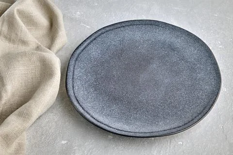 Gray ceramic plate and kitchen tablecloth on gray concrete table. Top view with Foto stock