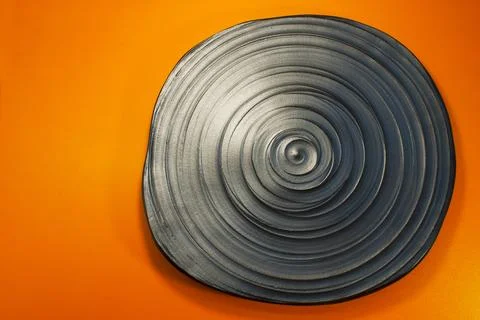 Gray ceramic plate with concentric spiral texture on orange background Stock Photos