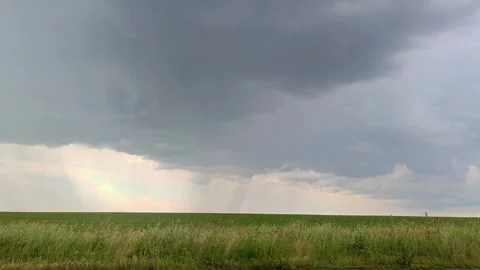 Gray clouds and pouring rain in green field Stock Footage 252926800
