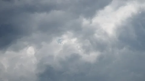 Gray clouds fill the sky and cover the sun. The clouds look thick as they move Stock Footage 335527503