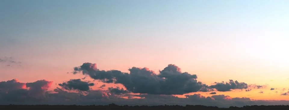 Gray clouds illuminated by the sun on a gradient sky background Stock Photos