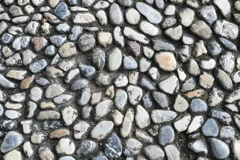 Gray cobblestone floor background with rounded stones of different shapes. Pe Stock Photos